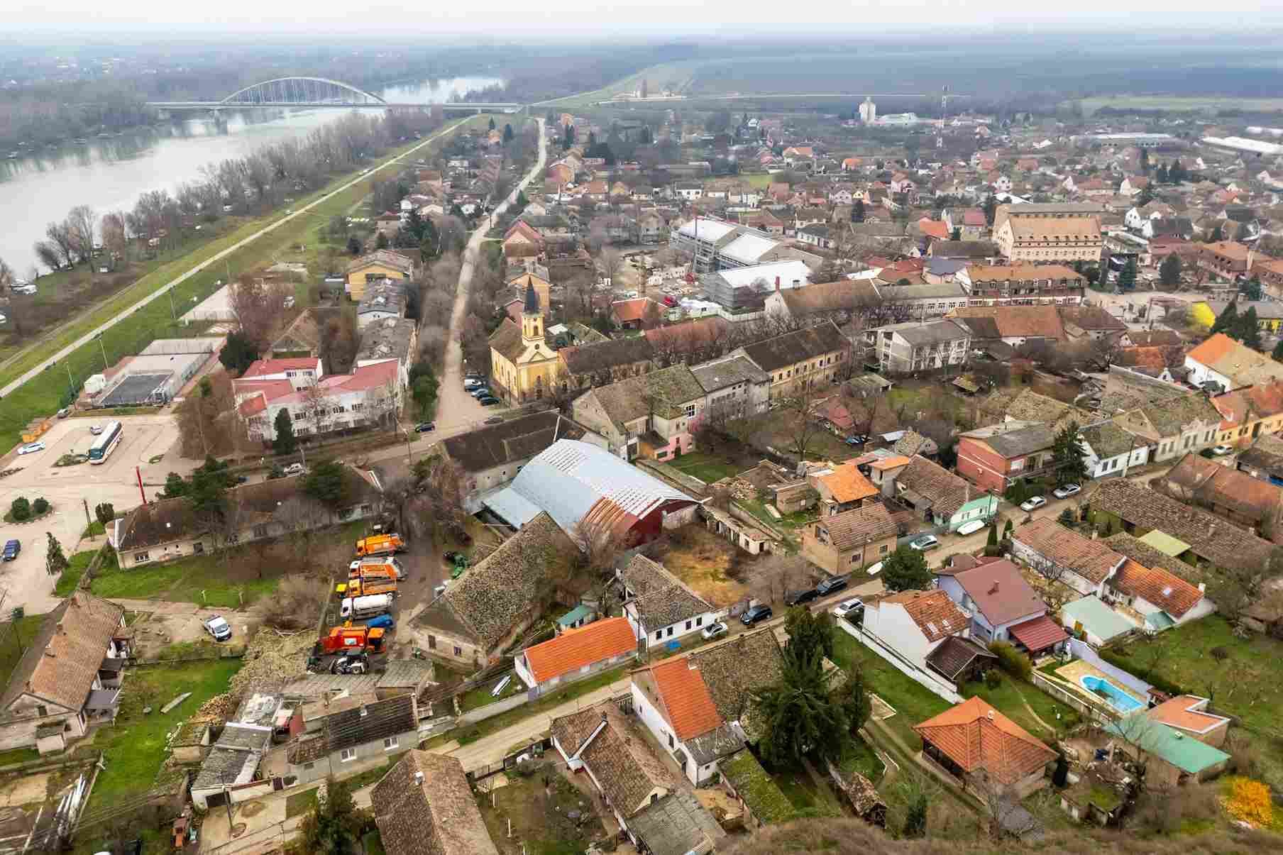 Aerial view of a small town near a river with a bridge and houses